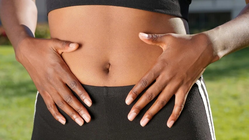 a woman wearing sports wear holding her arm around her waist