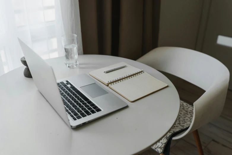 laptop computer on a white table next to a glass