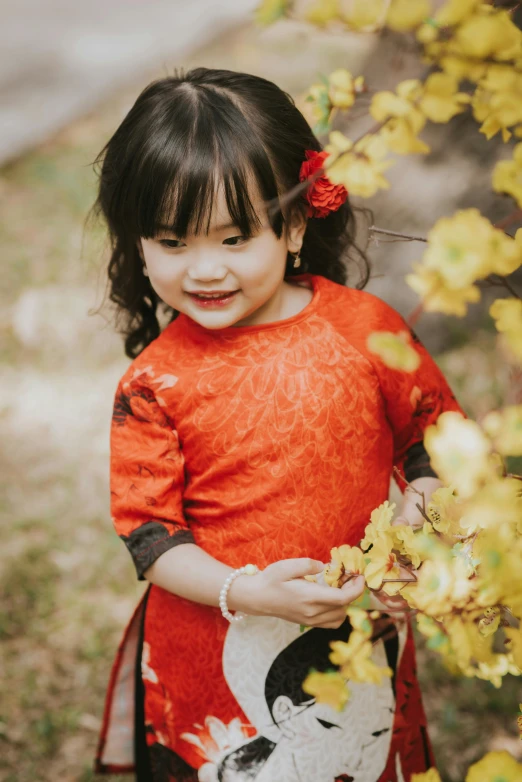 a little girl that is holding onto some yellow flowers