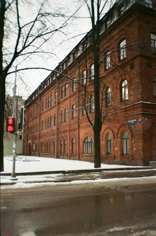 an old brick building with snow on it and a red traffic light at the corner