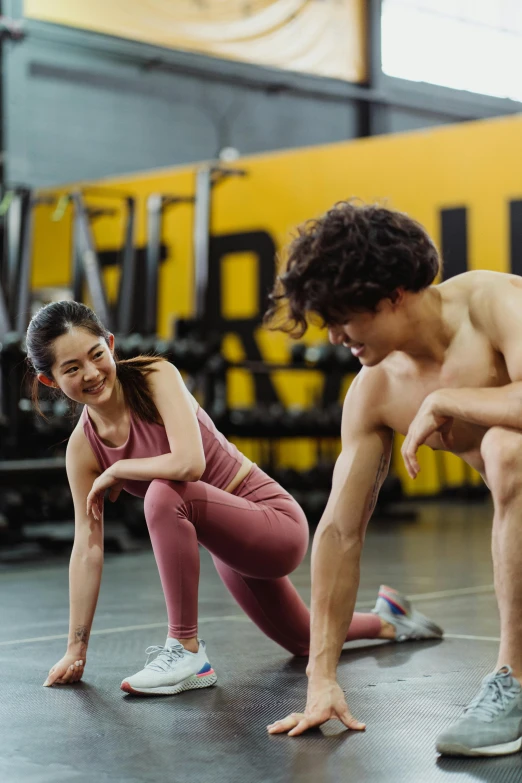 two fit women squatting and smiling in the gym