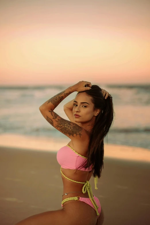 a beautiful woman wearing a bikini top and matching panties standing on the beach at sunset