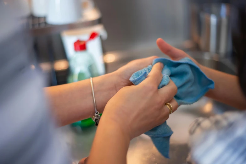 a woman in white shirt wiping her hands with blue gloves