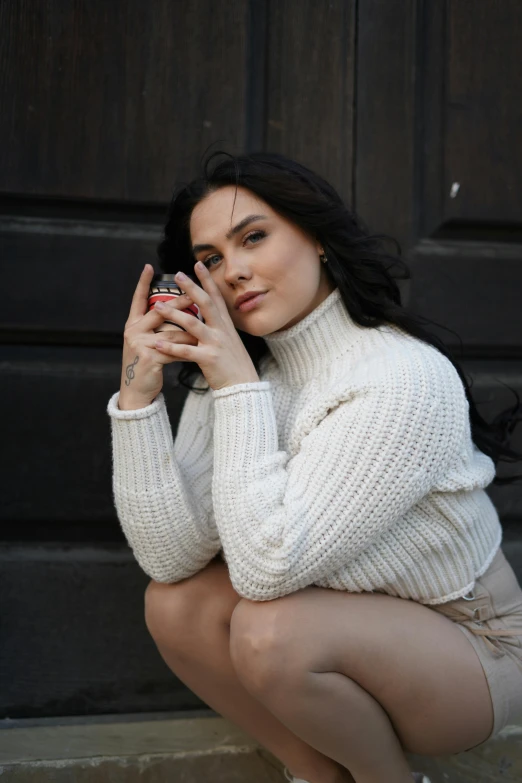 a woman with dark hair, white sweater and heels