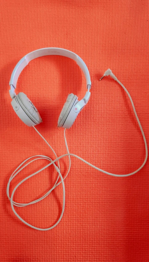 white headphones lie on an orange blanket