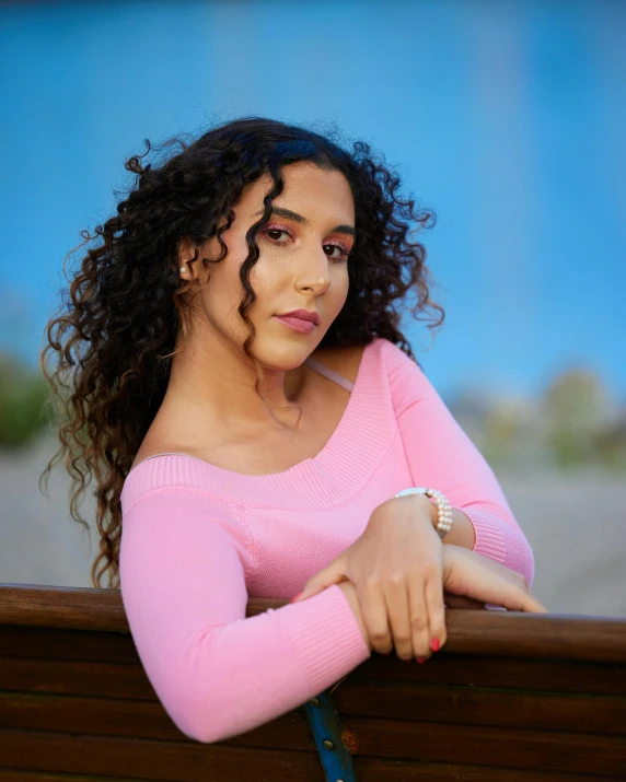 a woman with curly hair sitting on a wooden bench