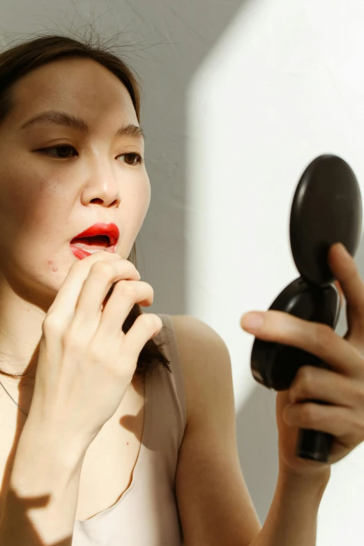 the young woman holds onto the brush while looking in the mirror