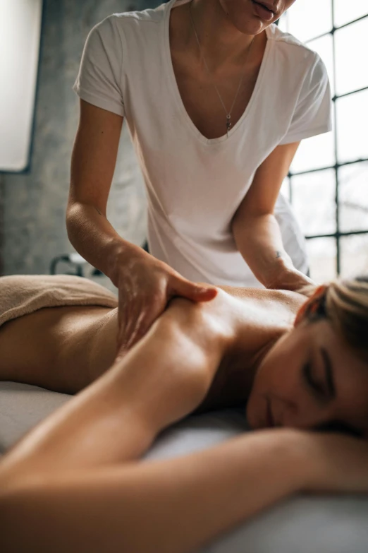 a woman receiving a back massage from a massage instructor