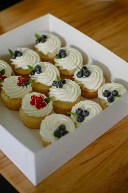 a white cupcake with fresh fruit on it sitting in a box