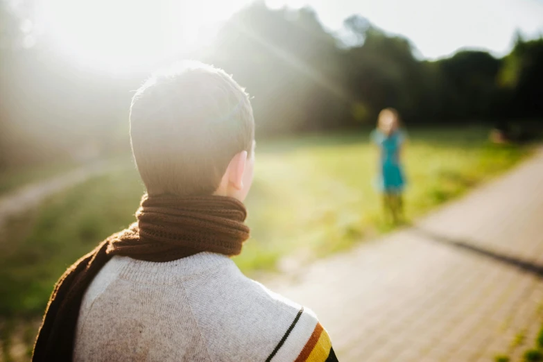 a boy with a scarf on stands outside near another person