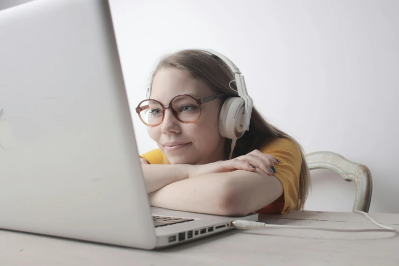 a person wearing headphones and leaning their head over a laptop
