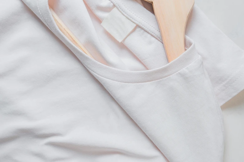 an unkempt white shirt with a wooden hanger next to it