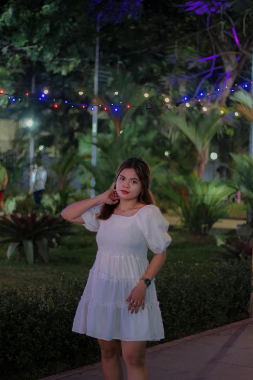 a woman is posing in white dress on a cell phone