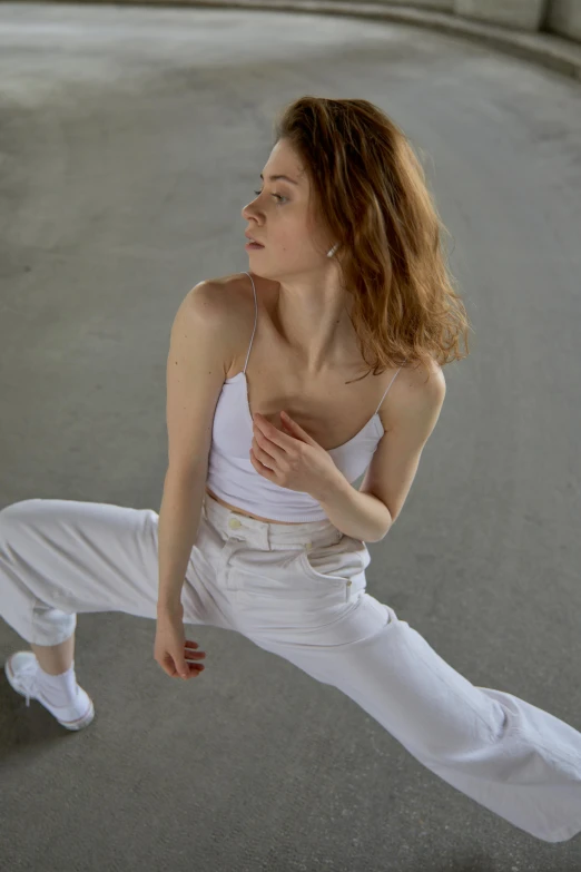 a woman dressed in white poses in the middle of a street