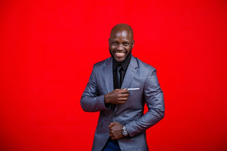 a man in a suit stands in front of a red background