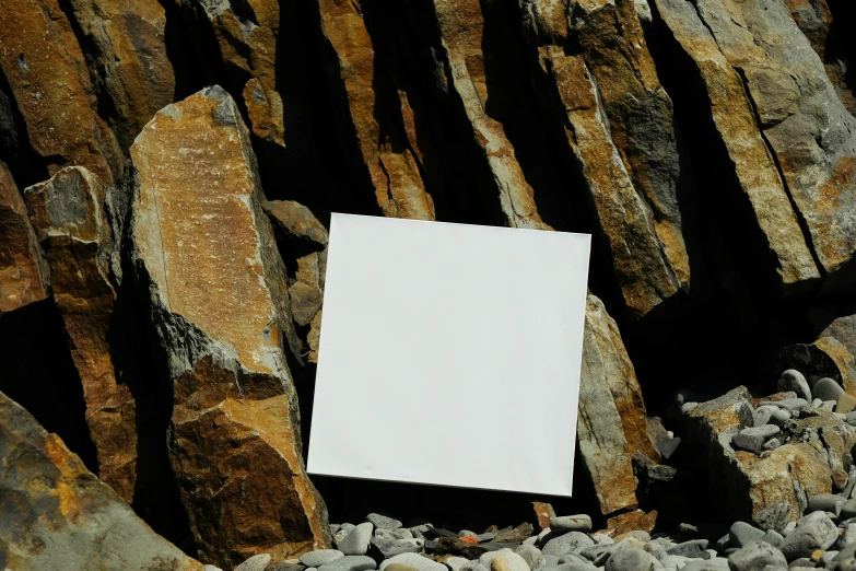 white square sign between some large rock