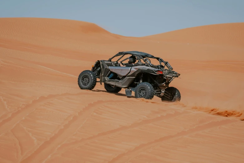 an off - road car rides through the desert on an orange sand dune