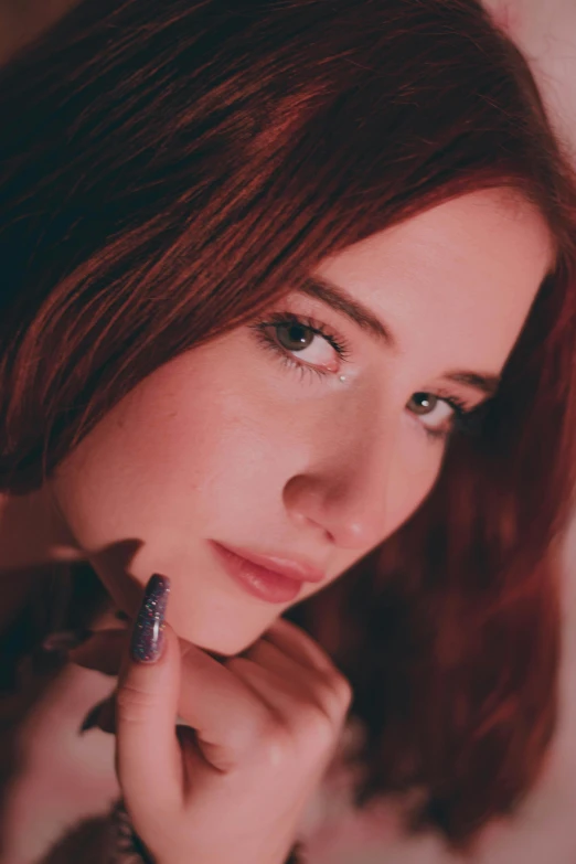 a young woman looks at the camera with her hand on her chin