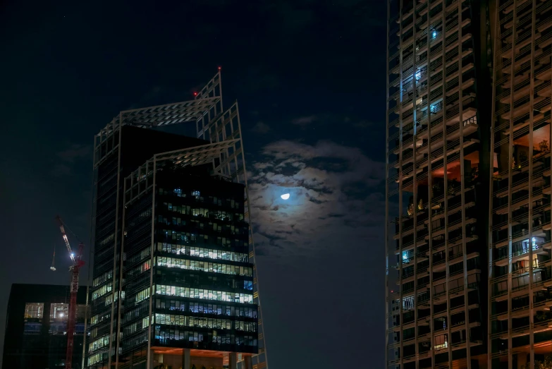 the moon is shining above a night - time cityscape