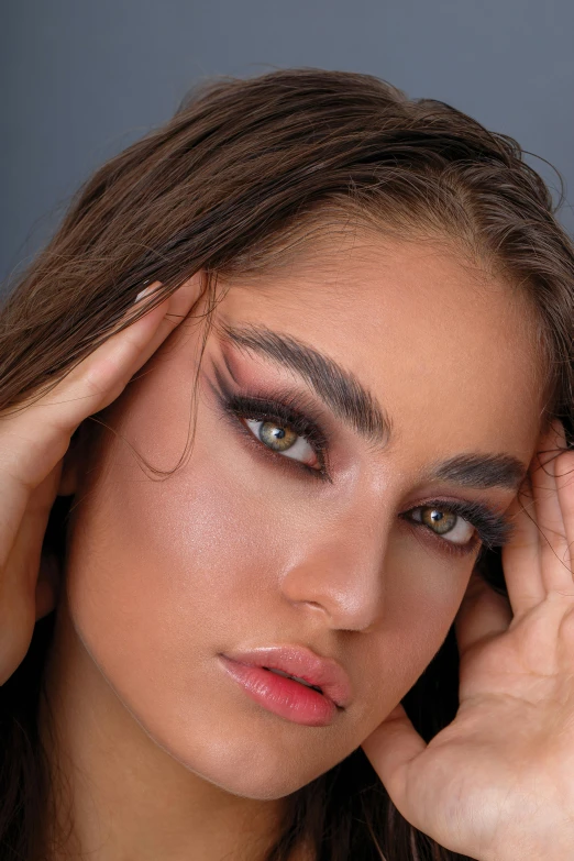 a woman with artistic make up holding her hand on the forehead