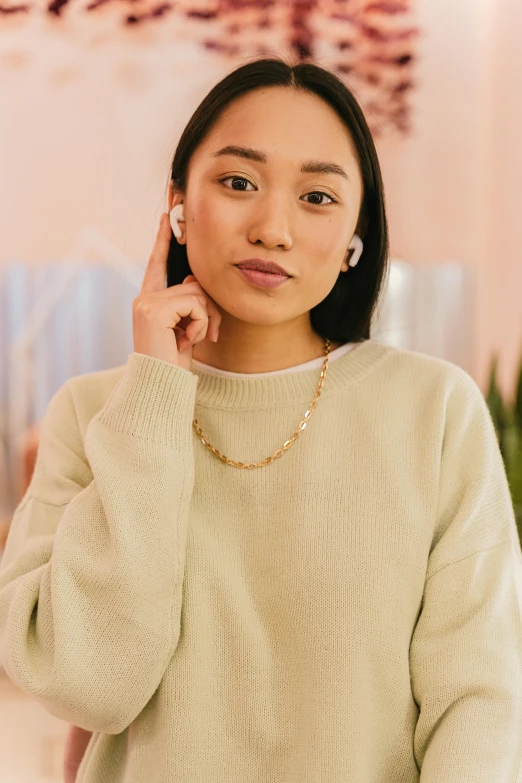 a woman poses for the camera while holding her hand under her ear