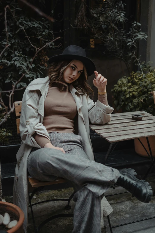 a woman sitting down on a bench with a hat on