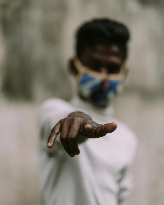 a person pointing with their hand while wearing a mask