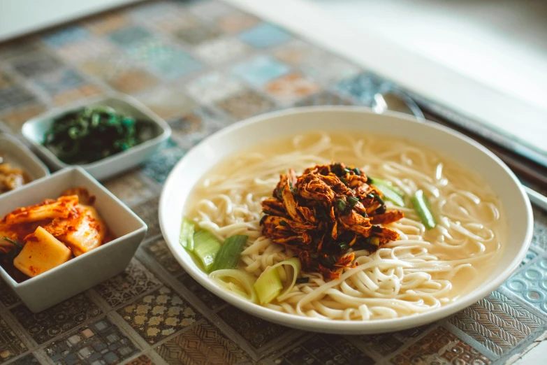 a white bowl of noodles with other dishes on the side