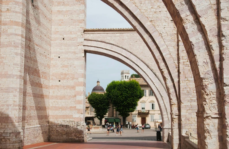 a large arch between two buildings with many people walking