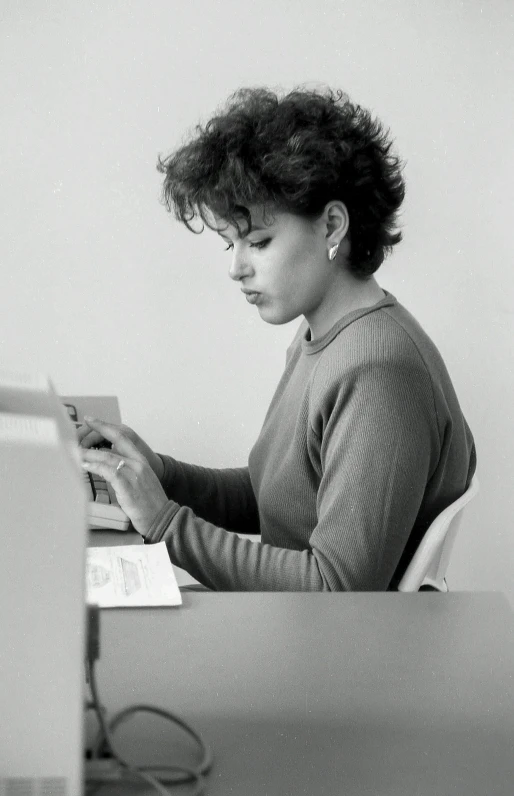 woman at computer using laptop, possibly typing on paper