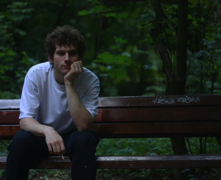 a man sits on the edge of a park bench