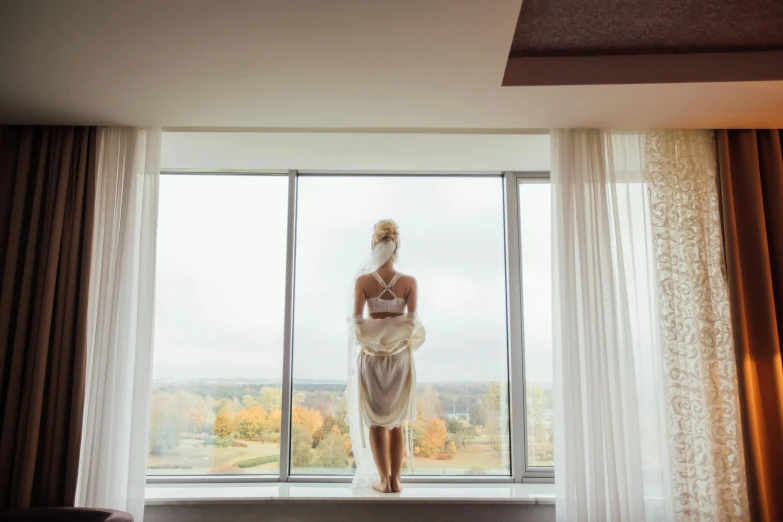 woman standing in front of window looking out to fall foliage