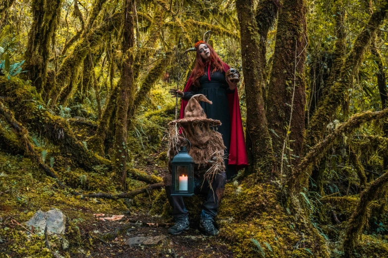 a man dressed up as a clown with a lantern in a forest