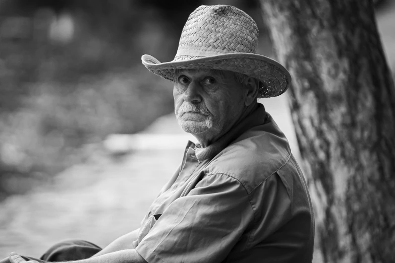 a man sitting under a tree in a hat