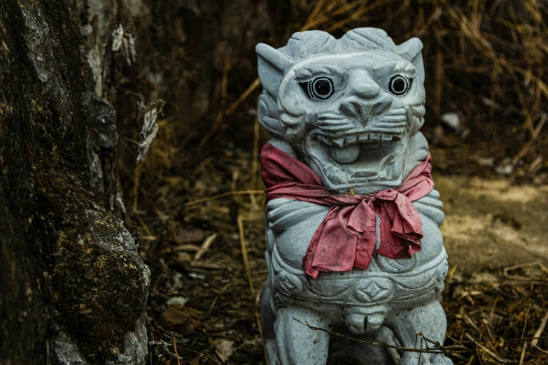 a statue sitting on the ground next to a tree