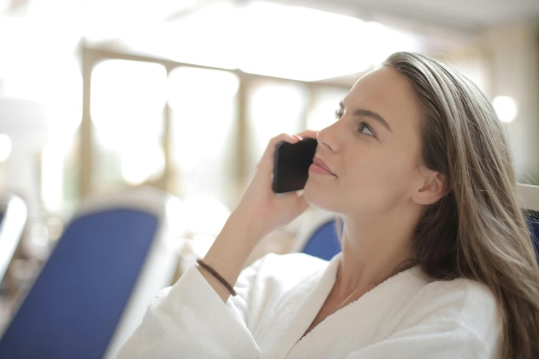 a woman is sitting in a blue chair talking on the phone