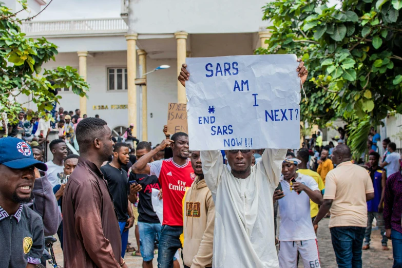 a group of people holding a sign and wearing blue on the street