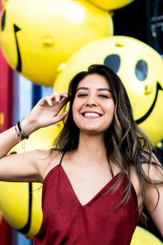 the woman is posing for a po in front of a bunch of smiley face balloons