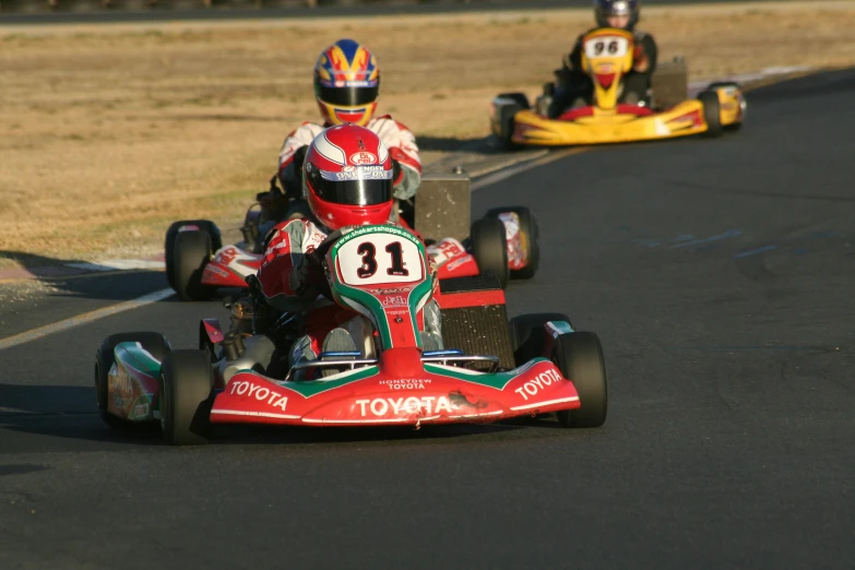 three go kart drivers are in motion on the road