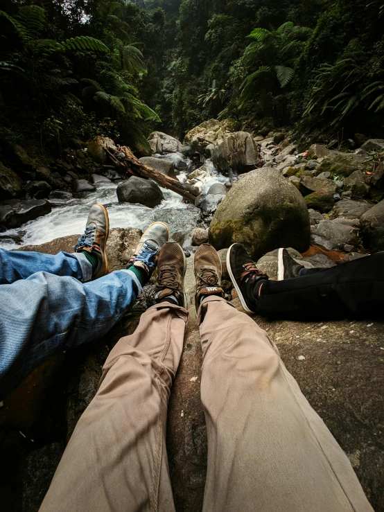 feet propped up over some rocks in front of a creek