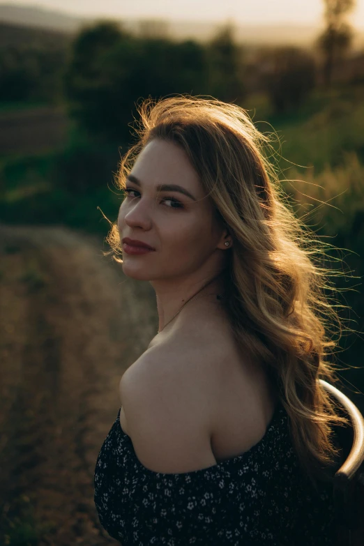 a woman in floral shirt posing on dirt road