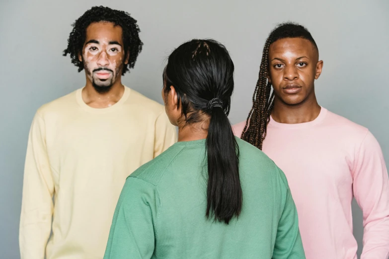 three people stand against a gray background with fake heads on