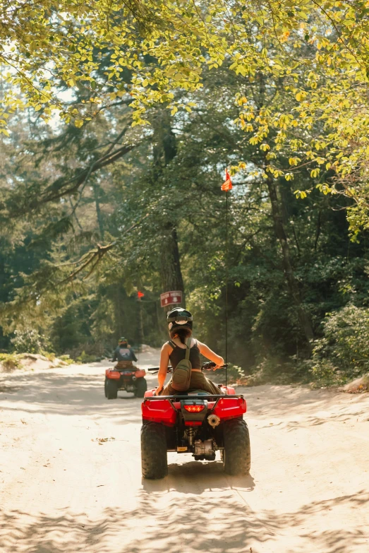 the people are riding four wheelers on the dirt road