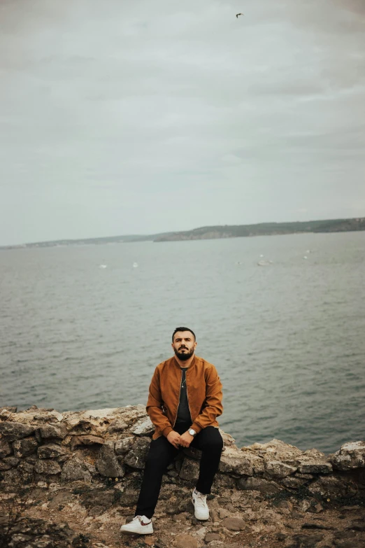 a man is sitting on rocks by the water