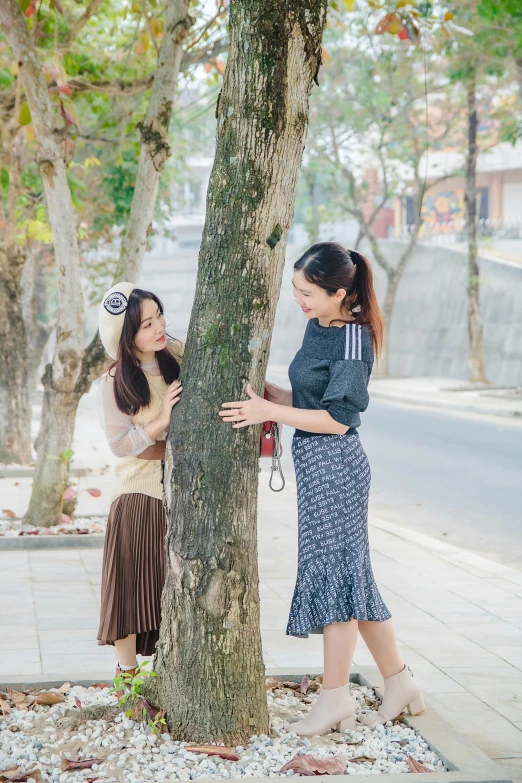 two women standing by a tree talking