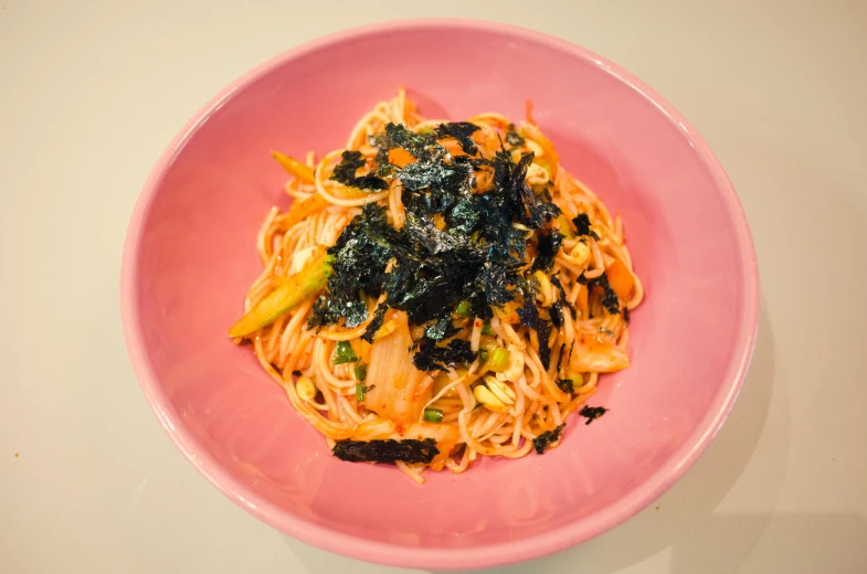 this pink plate contains spaghetti with spinach