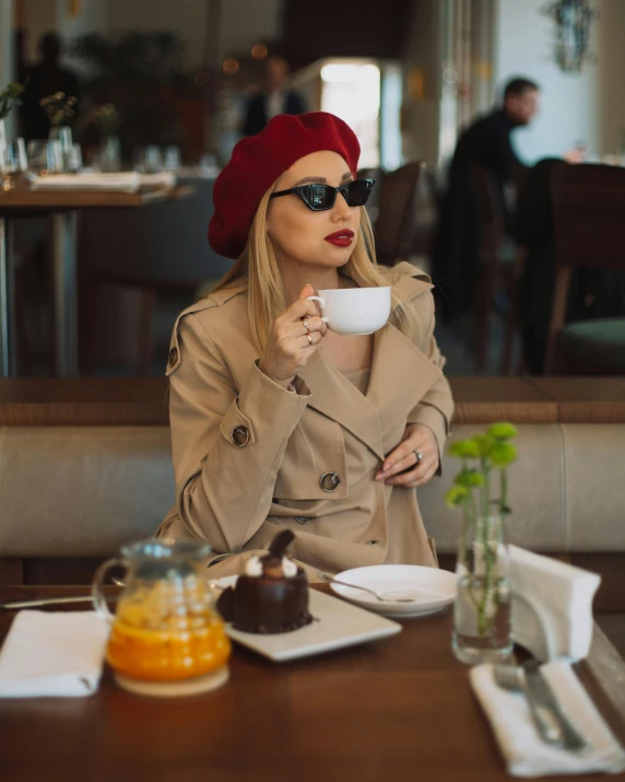 a young woman in a red hat drinking coffee