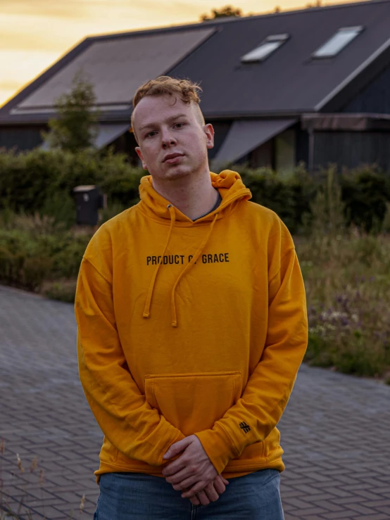 a young man standing on the sidewalk in front of a house