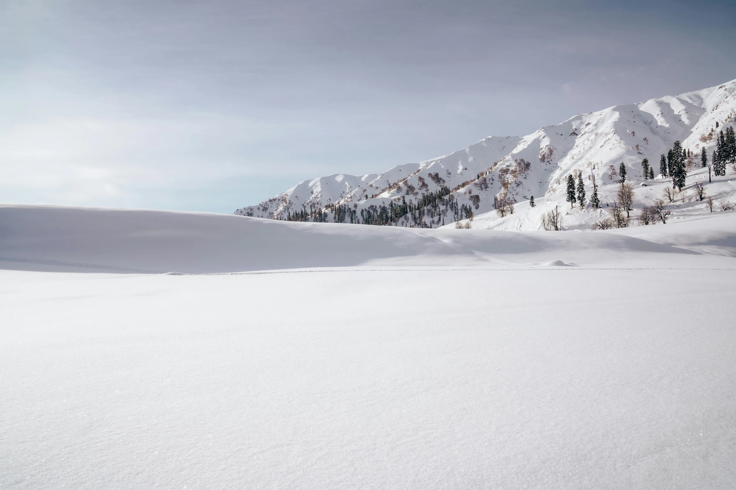 a snow covered field and several mountains in the distance