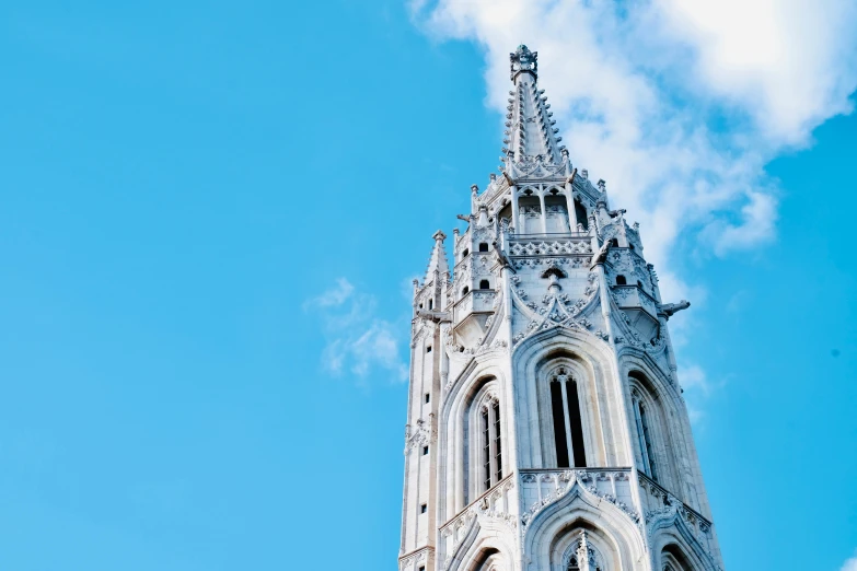 a tall white church tower standing under a blue cloudy sky